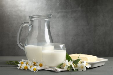 Photo of Fresh dairy products and flowers on grey wooden table against textured background