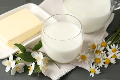 Photo of Fresh dairy products and flowers on grey table, closeup