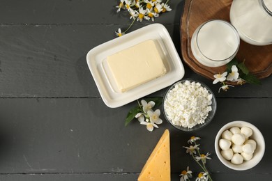 Photo of Fresh dairy products and flowers on grey wooden table, flat lay. Space for text