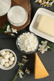Photo of Fresh dairy products and flowers on grey wooden table, flat lay