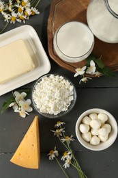 Photo of Fresh dairy products and flowers on grey wooden table, flat lay