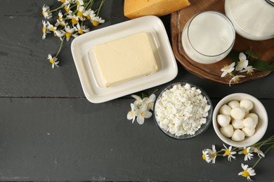 Photo of Fresh dairy products and flowers on grey wooden table, flat lay. Space for text