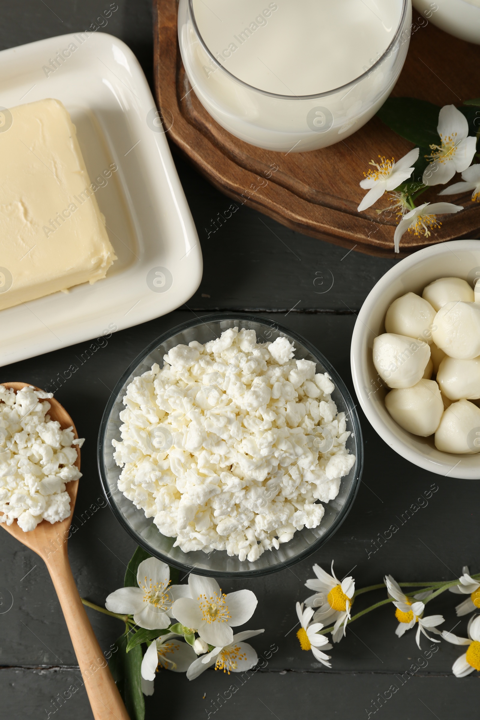 Photo of Fresh dairy products and flowers on grey wooden table, flat lay
