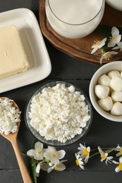 Photo of Fresh dairy products and flowers on grey wooden table, flat lay