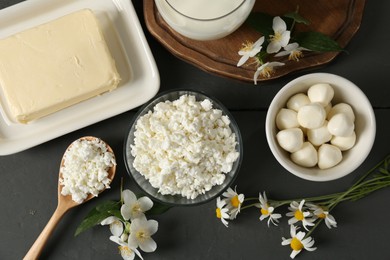 Photo of Fresh dairy products and flowers on grey wooden table, flat lay