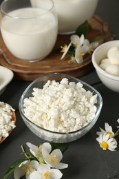 Photo of Fresh dairy products and flowers on grey wooden table, closeup