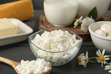 Photo of Fresh dairy products and flowers on grey wooden table, closeup
