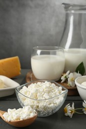 Photo of Fresh dairy products and flowers on grey wooden table against textured background, closeup