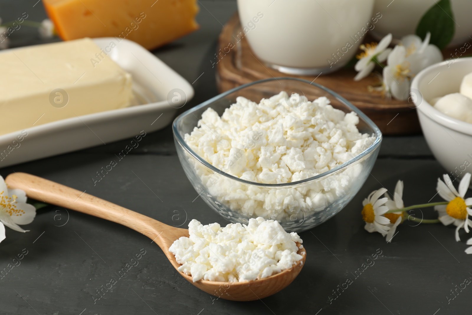 Photo of Fresh dairy products and flowers on grey wooden table, closeup