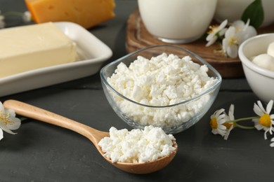 Photo of Fresh dairy products and flowers on grey wooden table, closeup