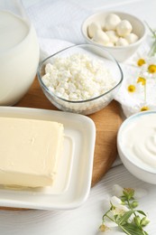Photo of Fresh dairy products and flowers on white wooden table, closeup