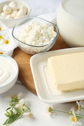 Photo of Fresh dairy products and flowers on white wooden table, closeup