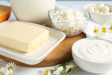 Photo of Fresh dairy products and flowers on white wooden table, closeup
