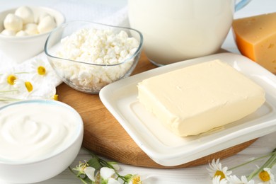 Photo of Fresh dairy products and flowers on white wooden table, closeup