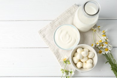 Photo of Fresh dairy products and flowers on white wooden table, flat lay. Space for text