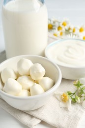 Photo of Fresh dairy products and flowers on white wooden table, closeup