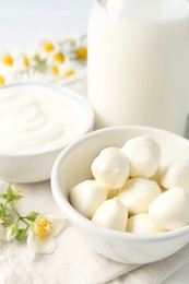 Photo of Fresh dairy products and flowers on white table, closeup