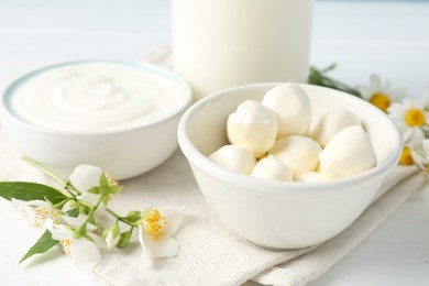 Photo of Fresh dairy products and flowers on white wooden table, closeup