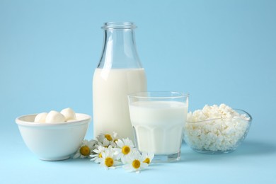 Photo of Fresh dairy products and chamomile flowers on light blue background