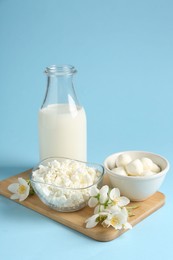 Photo of Fresh dairy products and jasmine flowers on light blue background
