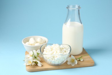 Photo of Fresh dairy products and jasmine flowers on light blue background