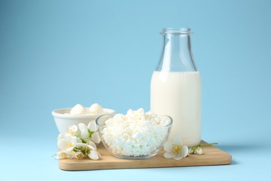 Photo of Fresh dairy products and jasmine flowers on light blue background