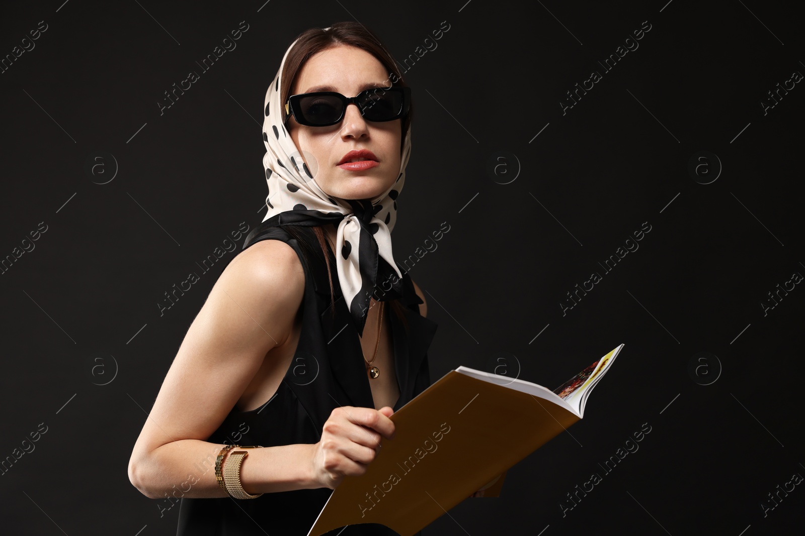 Beautiful woman in stylish outfit with fashion magazine on black background Photo of Beautiful woman in stylish outfit with fashion magazine on black background
