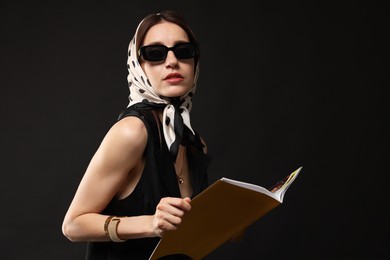 Photo of Beautiful woman in stylish outfit with fashion magazine on black background