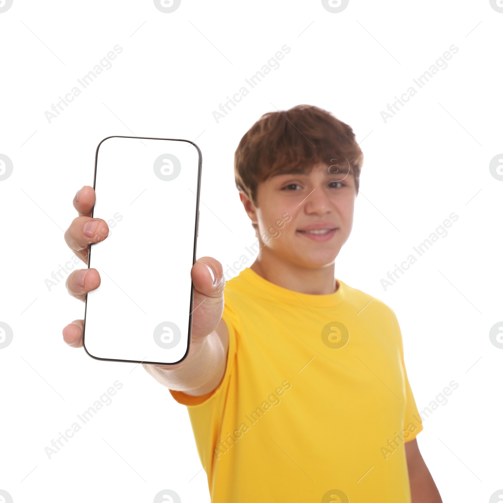Photo of Smiling teenage boy showing smartphone with blank screen on white background, selective focus. Mockup for design