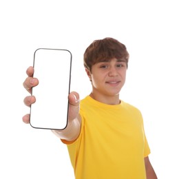 Photo of Smiling teenage boy showing smartphone with blank screen on white background, selective focus. Mockup for design
