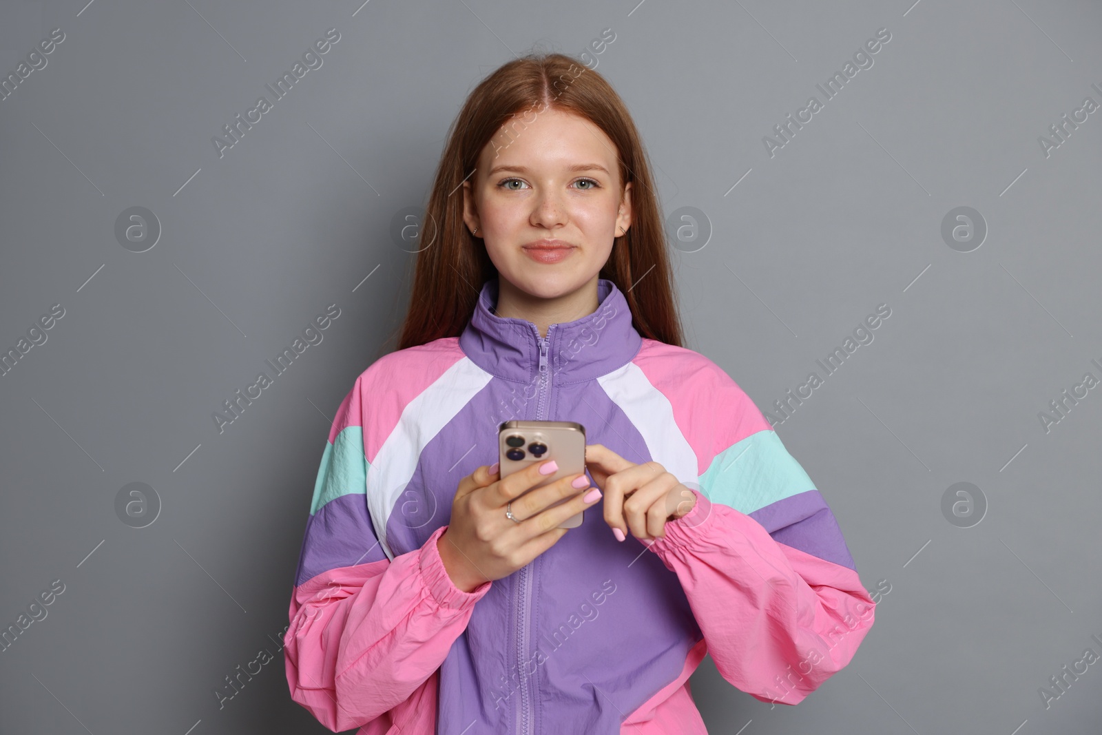 Beautiful teenage girl using smartphone on grey background Photo of Beautiful teenage girl using smartphone on grey background