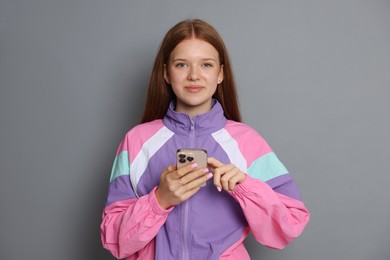Photo of Beautiful teenage girl using smartphone on grey background
