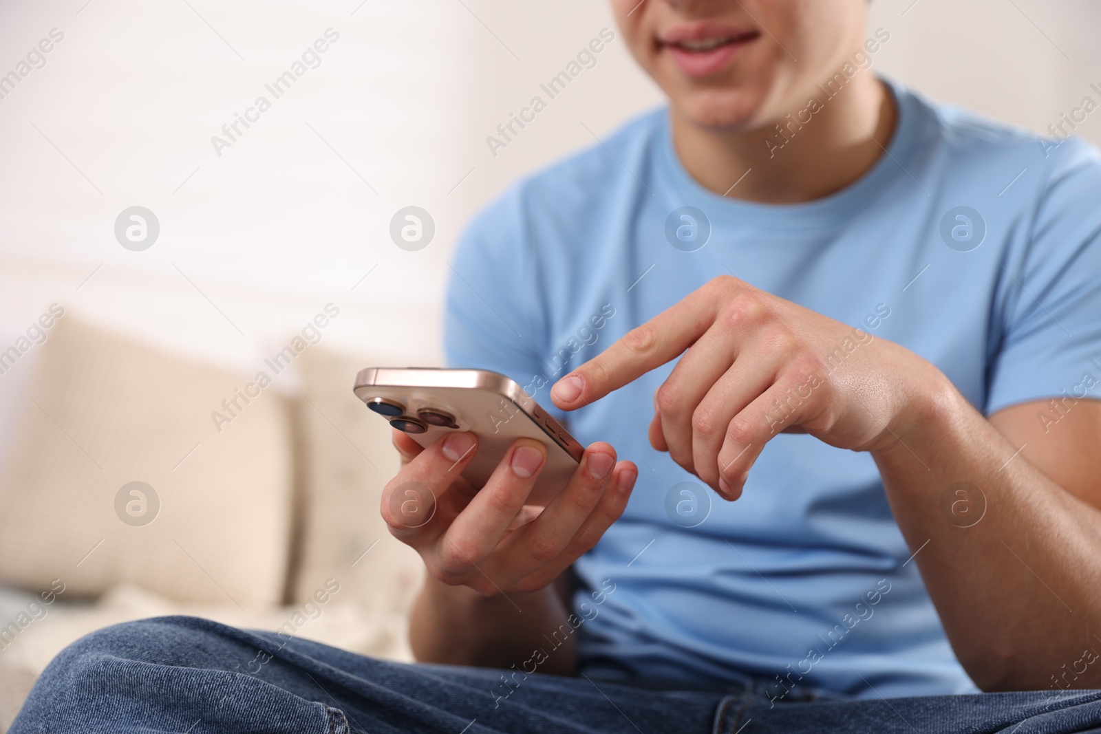 Photo of Smiling teenage boy using smartphone at home, closeup