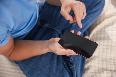 Photo of Teenage boy using smartphone on bed at home, closeup