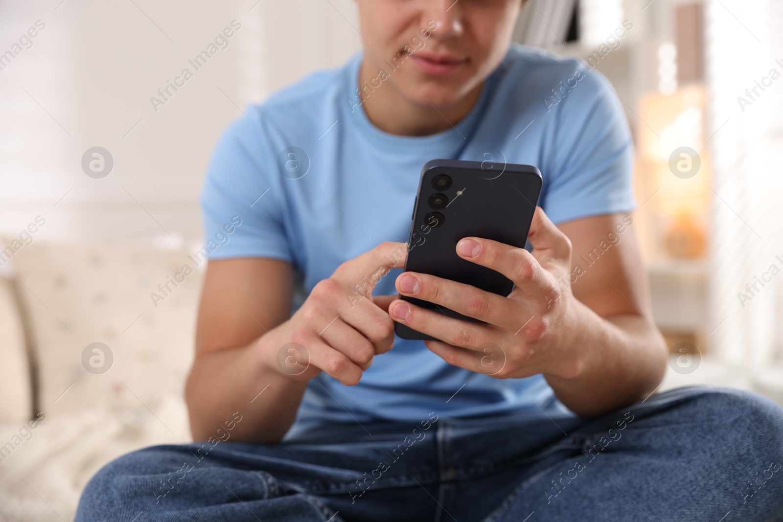 Photo of Teenage boy using smartphone on bed at home, closeup