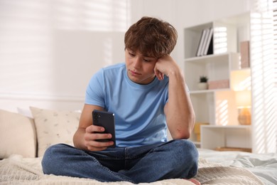 Photo of Teenage boy using smartphone on bed at home