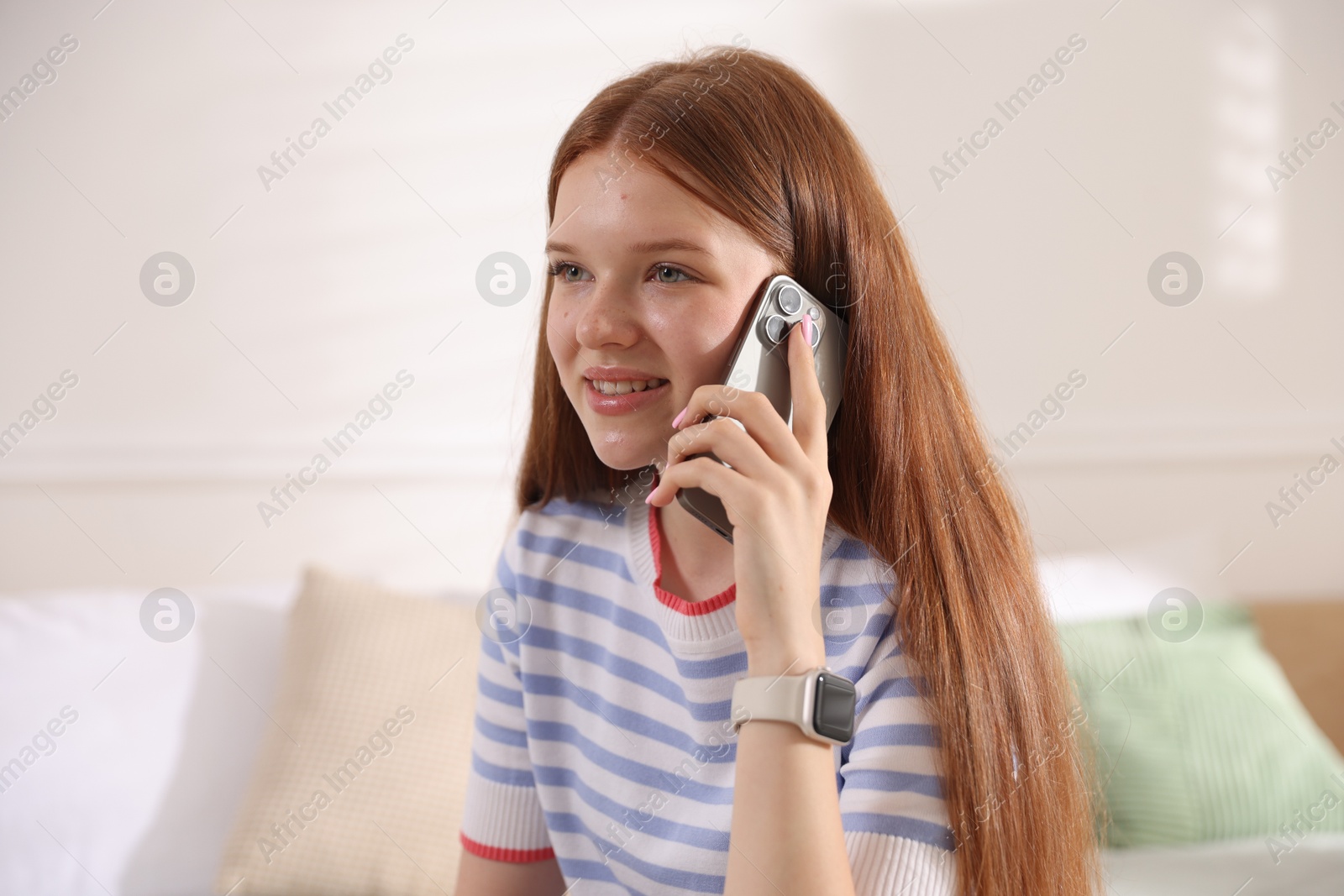 Smiling teenage girl talking by smartphone at home Photo of Smiling teenage girl talking by smartphone at home
