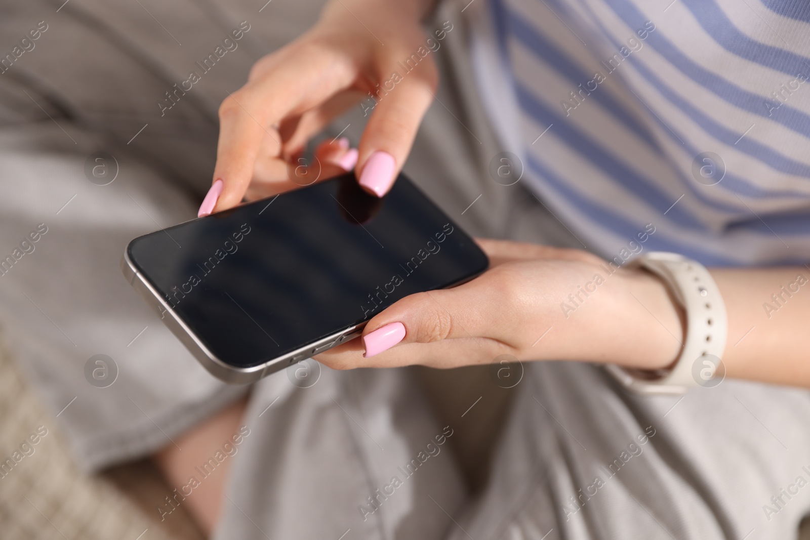 Photo of Teenage girl using smartphone on bed at home, closeup