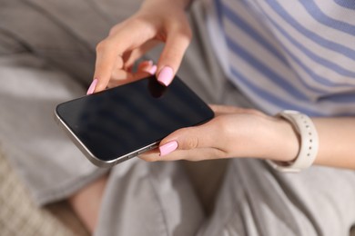 Photo of Teenage girl using smartphone on bed at home, closeup