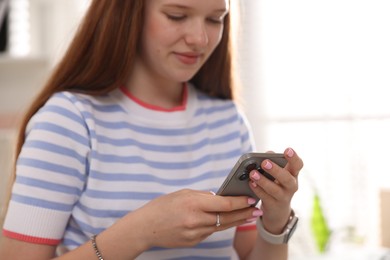 Photo of Beautiful teenage girl with smartphone at home