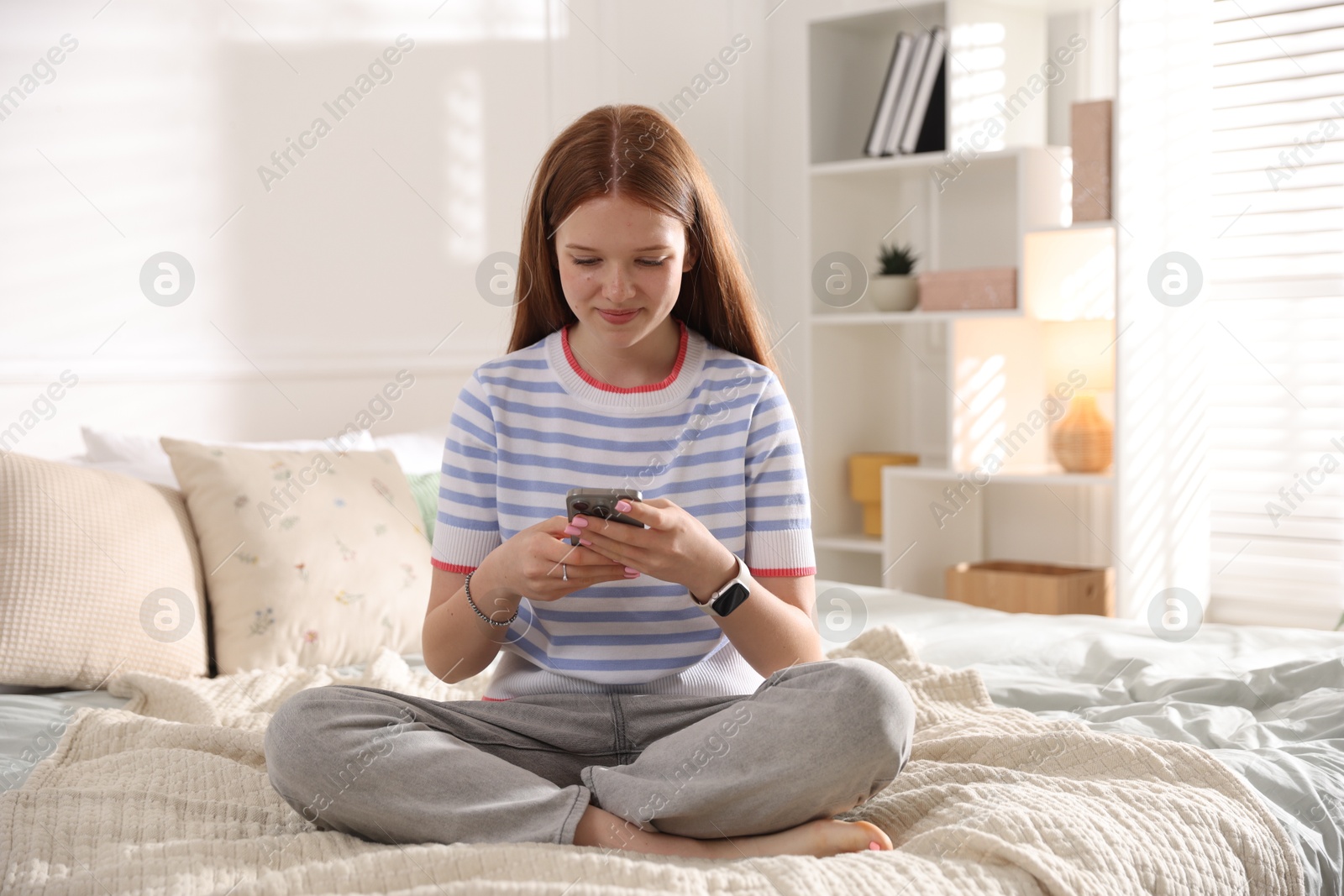 Teenage girl using smartphone on bed at home Photo of Teenage girl using smartphone on bed at home