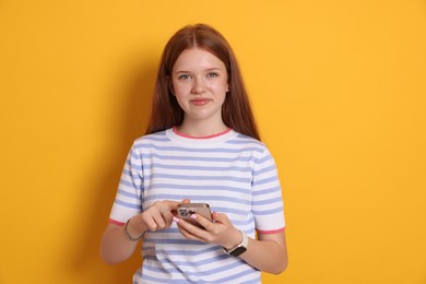 Photo of Beautiful teenage girl using smartphone on yellow background