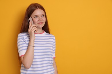 Photo of Beautiful teenage girl talking by smartphone on yellow background. Space for text