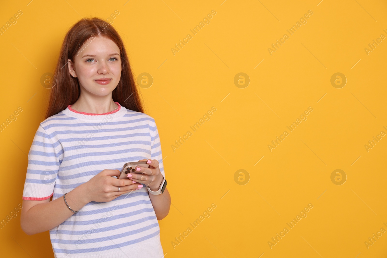 Beautiful teenage girl with smartphone on yellow background. Space for text Photo of Beautiful teenage girl with smartphone on yellow background. Space for text