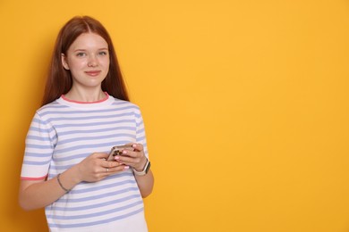 Photo of Beautiful teenage girl with smartphone on yellow background. Space for text