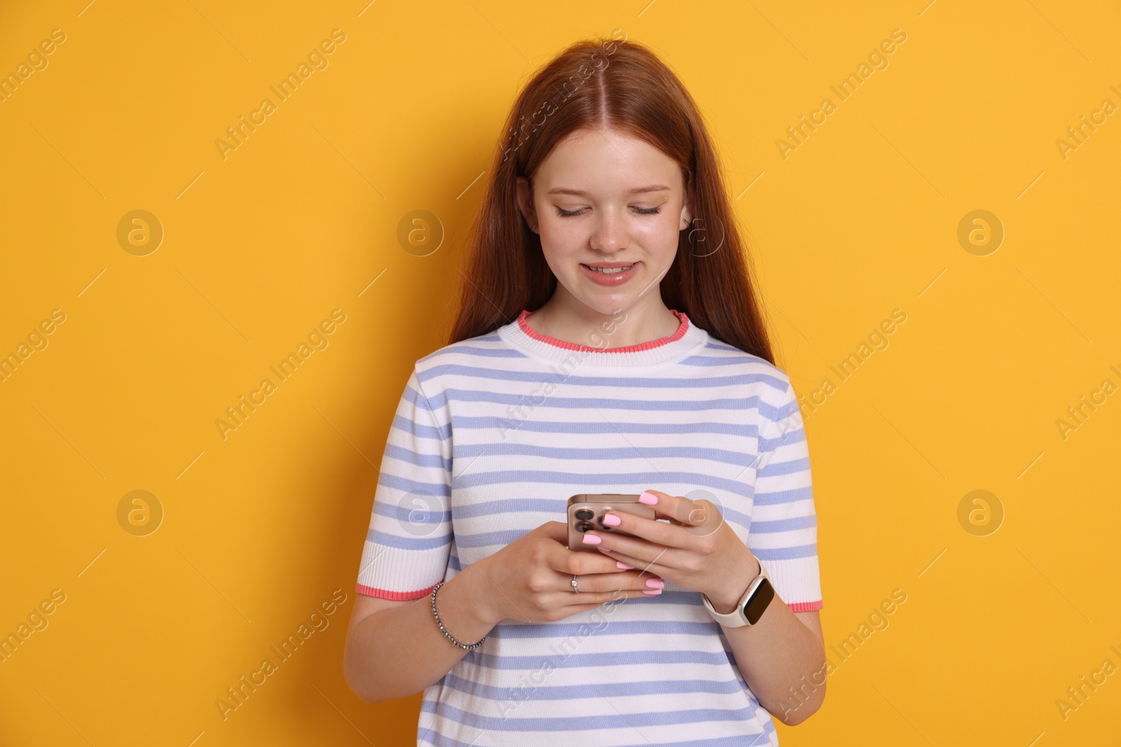Smiling teenage girl using smartphone on yellow background Photo of Smiling teenage girl using smartphone on yellow background