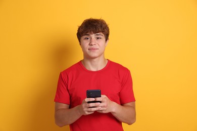 Photo of Portrait of teenage boy with smartphone on yellow background