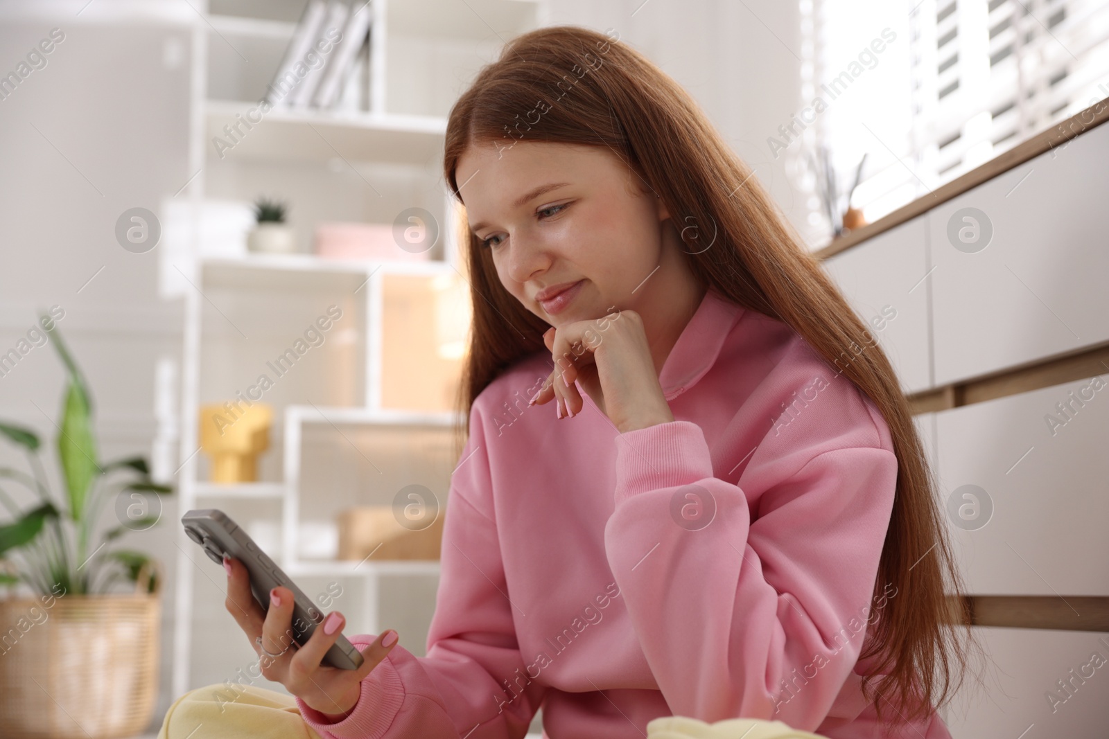 Beautiful teenage girl using smartphone at home Photo of Beautiful teenage girl using smartphone at home