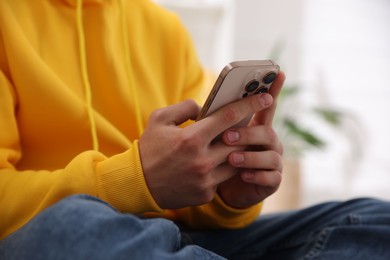 Photo of Teenage boy using smartphone at home, closeup