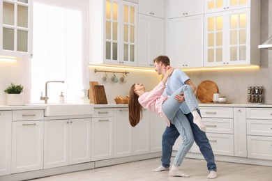Photo of Happy young couple dancing together in kitchen